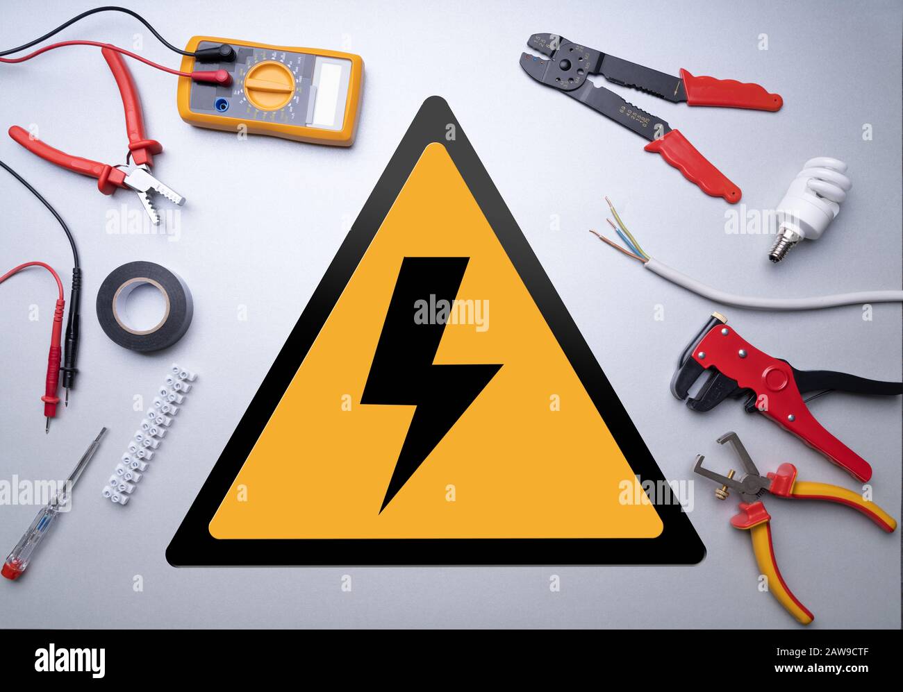 Various Electrician Tools Set Around High Voltage Sign On Gray Background Stock Photo