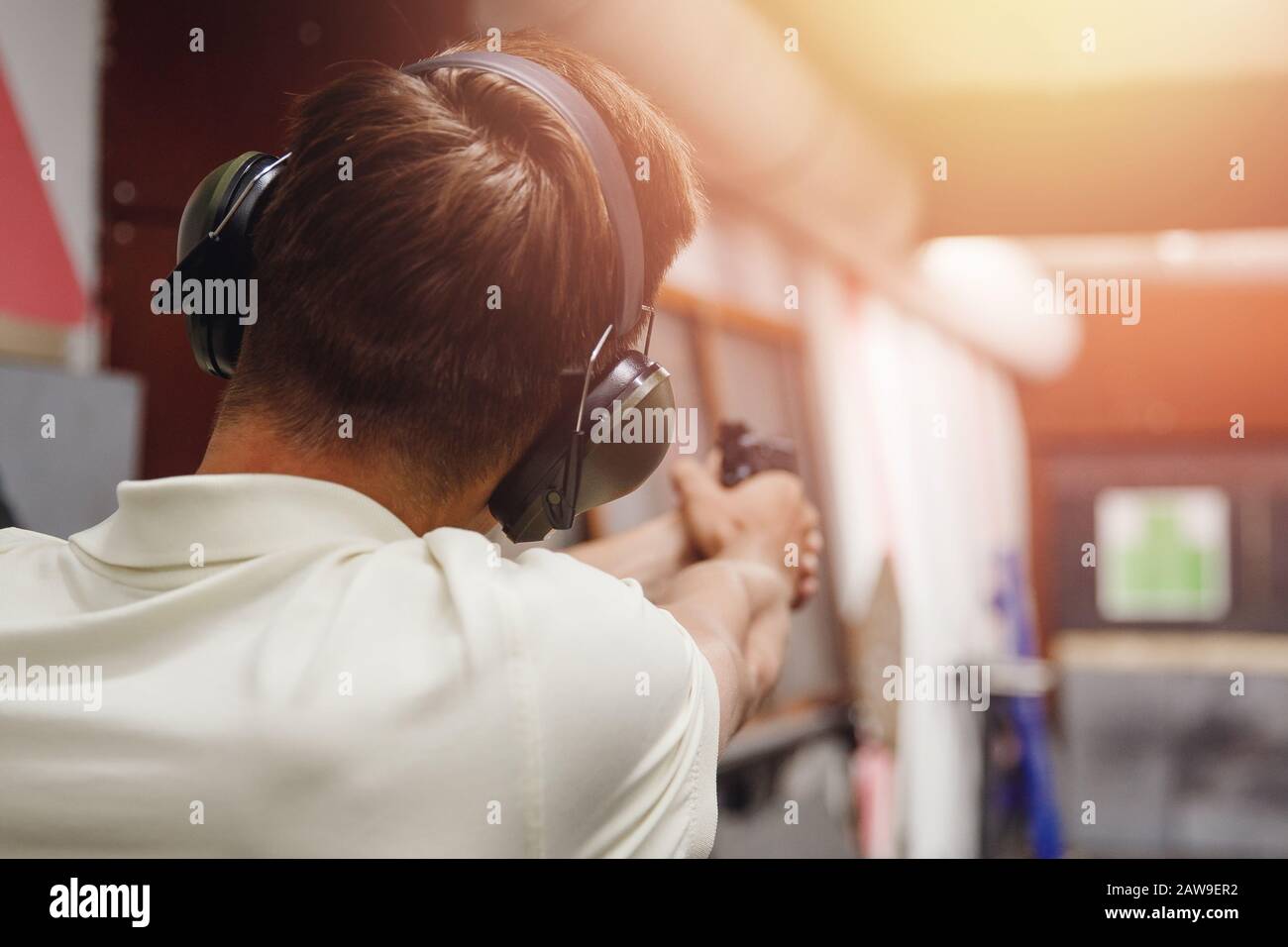 Shooting range gun. Man shoots pistol in noise protection headphones