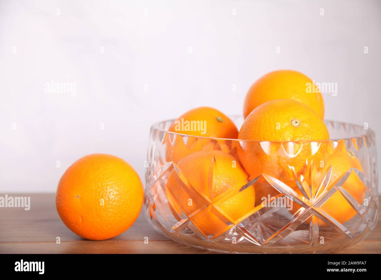 Lead crystal fruit bowl full of oranges 'fruit' against white background with copy space Stock Photo