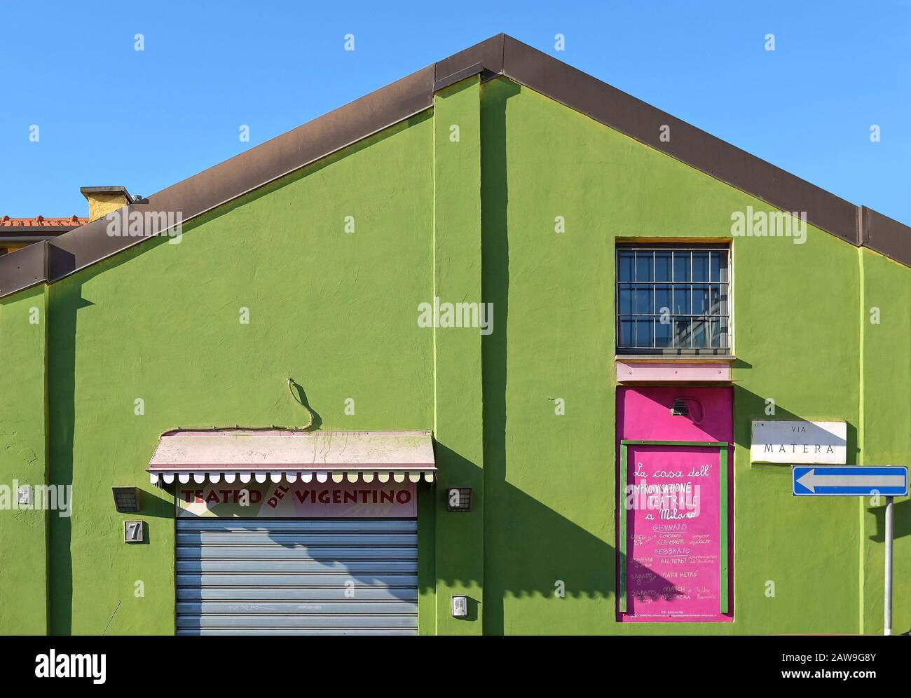 Old-fashioned factory shed with with a deep green facade on a blue sky, now used as a theatre of Vigentino, in the southern suburbs of Milan, Italy Stock Photo