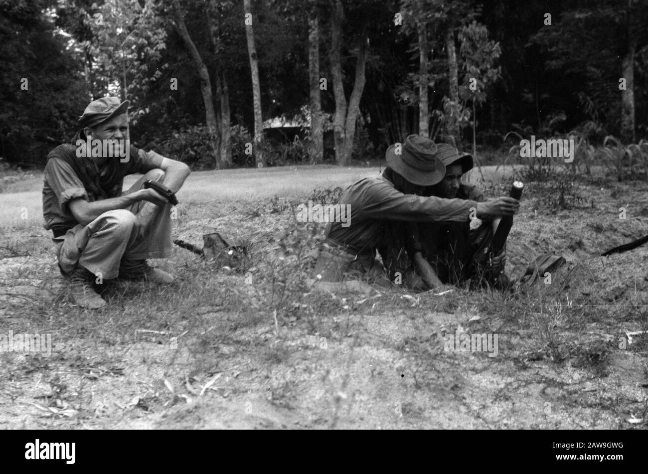 Tapanoeli [2nd Police Action]  [right two soldiers with a light mortar. Left watching a machine gunner far, with his hand a magazine with bullets and his shoulders a camouflage scarf] Date: December 25, 1948 Location: Indonesia, Dutch East Indies, Sumatra Stock Photo