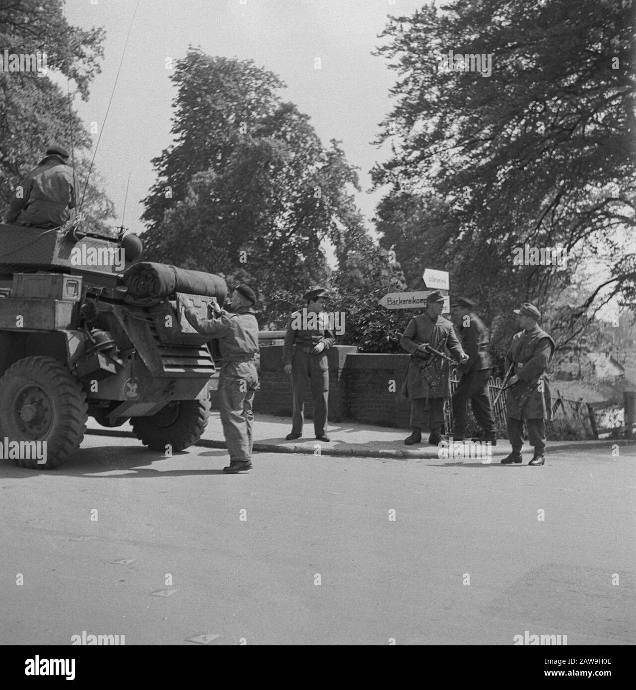 Liberation Joy: Amersfoort  Armored Car of the 49th West Riding Infantry Division on a bridge with signs in German. On the side are still armed German soldiers Date: May 7, 1945 Location: Amersfoort Keywords: Liberation, World War II Stock Photo