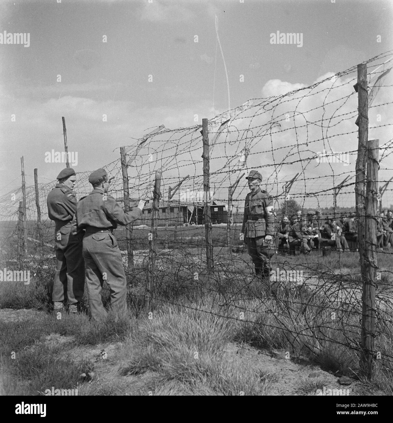 Capitulation: Harskamp [camp where SS and National Guards are interned]  Soldiers at the barbed wire Annotation: In this camp were about 4,000 Dutch SS prisoners housed (including Army, Landstorm , Viking, Germania, Holl Grüne Polizei etc.) their trials awaited. Date: June 1945 Location: Gelderland, Harskamp Keywords: internment camps, prisoner of war, soldiers Stock Photo