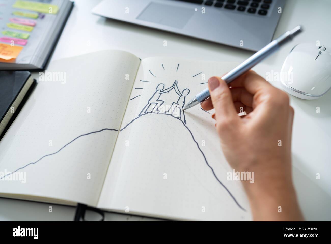 Businesswoman Drawing The Figures Giving High Five On Notebook Stock Photo