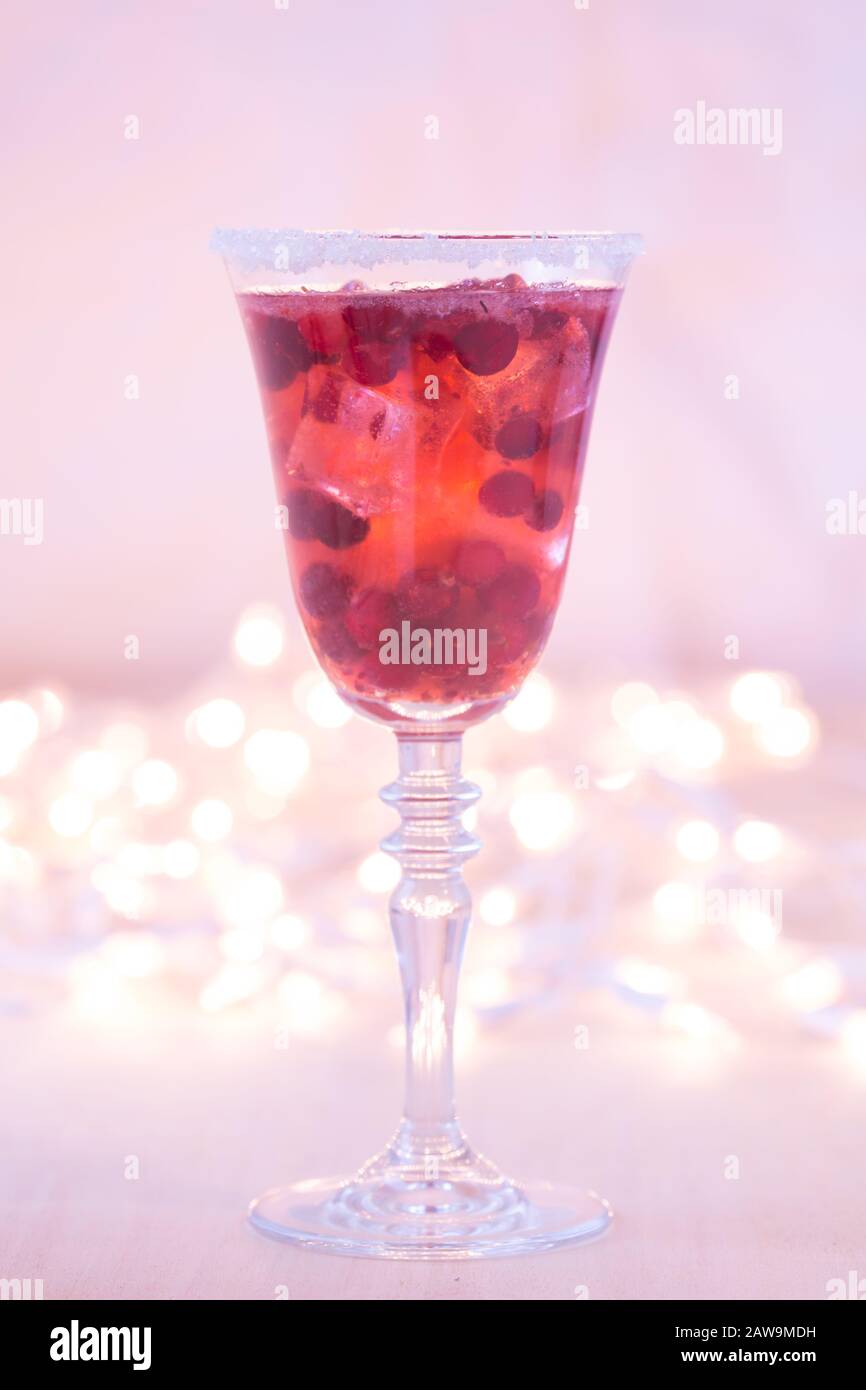 Glass of champagne and cranberry cocktail, macro. Lightweight background. Christmas mood. Vintage style. Shifted white balance, warm lilac tone. Vertical Stock Photo