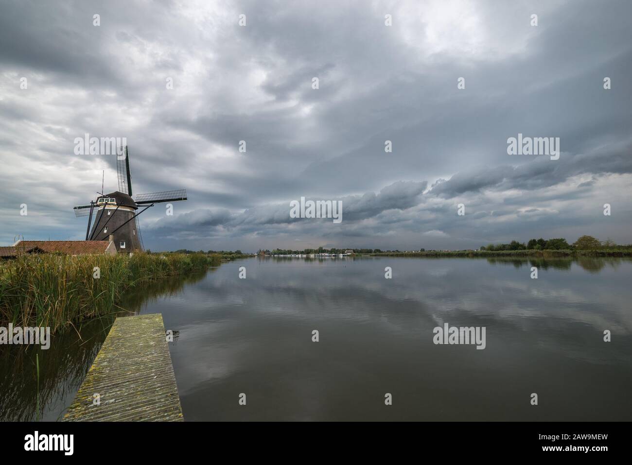 Shelf cloud of a thunderstorm over the river RotteNetherlands. Scenic landscape image with classic dutch windmill and calm water before the storm. Stock Photo