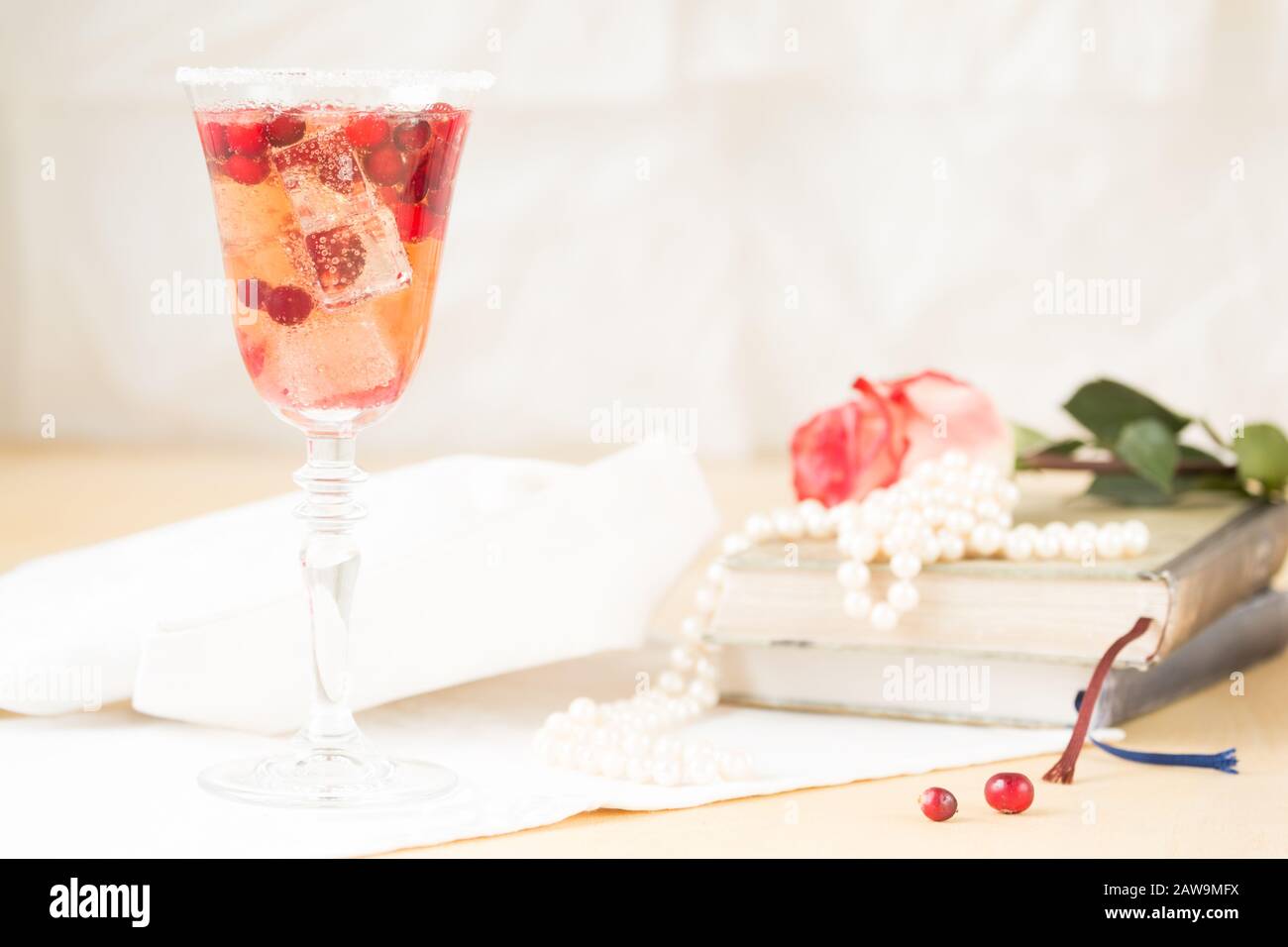Glass of champagne and cranberry cocktail with vintage books and pearls. Lightweight background. Vintage style. Horizontal Stock Photo