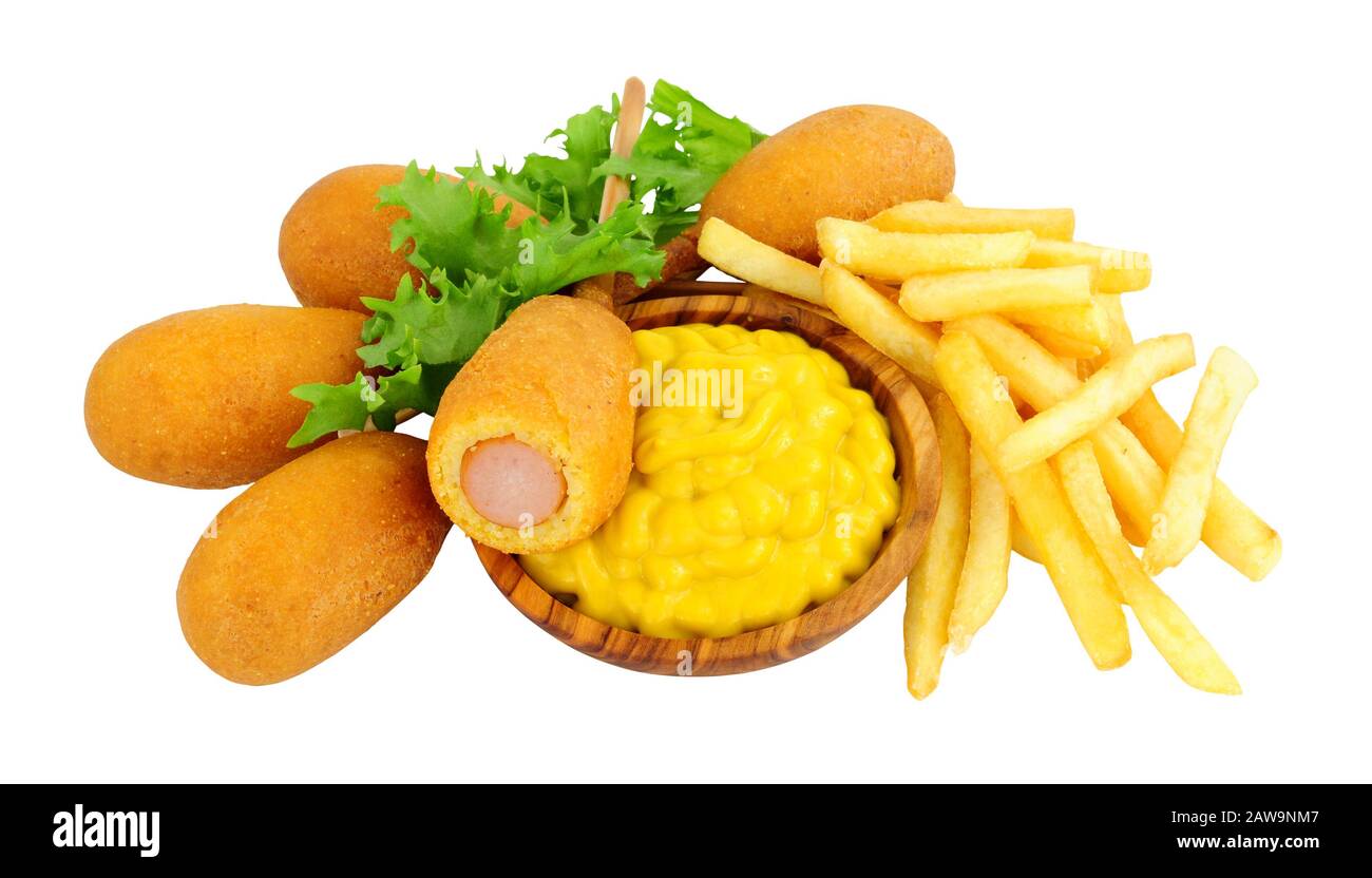 Mini party corn dogs on wooden sticks and French fries with a wooden bowl of American mustard isolated on a white background Stock Photo