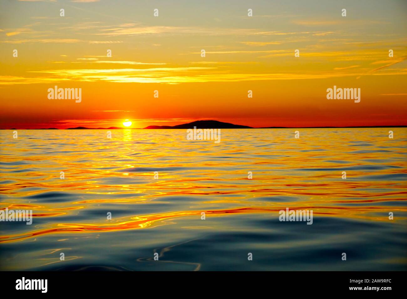 Orange and gold color tone beautiful sunset above the golden and blue sea surface on the island at the summer Stock Photo