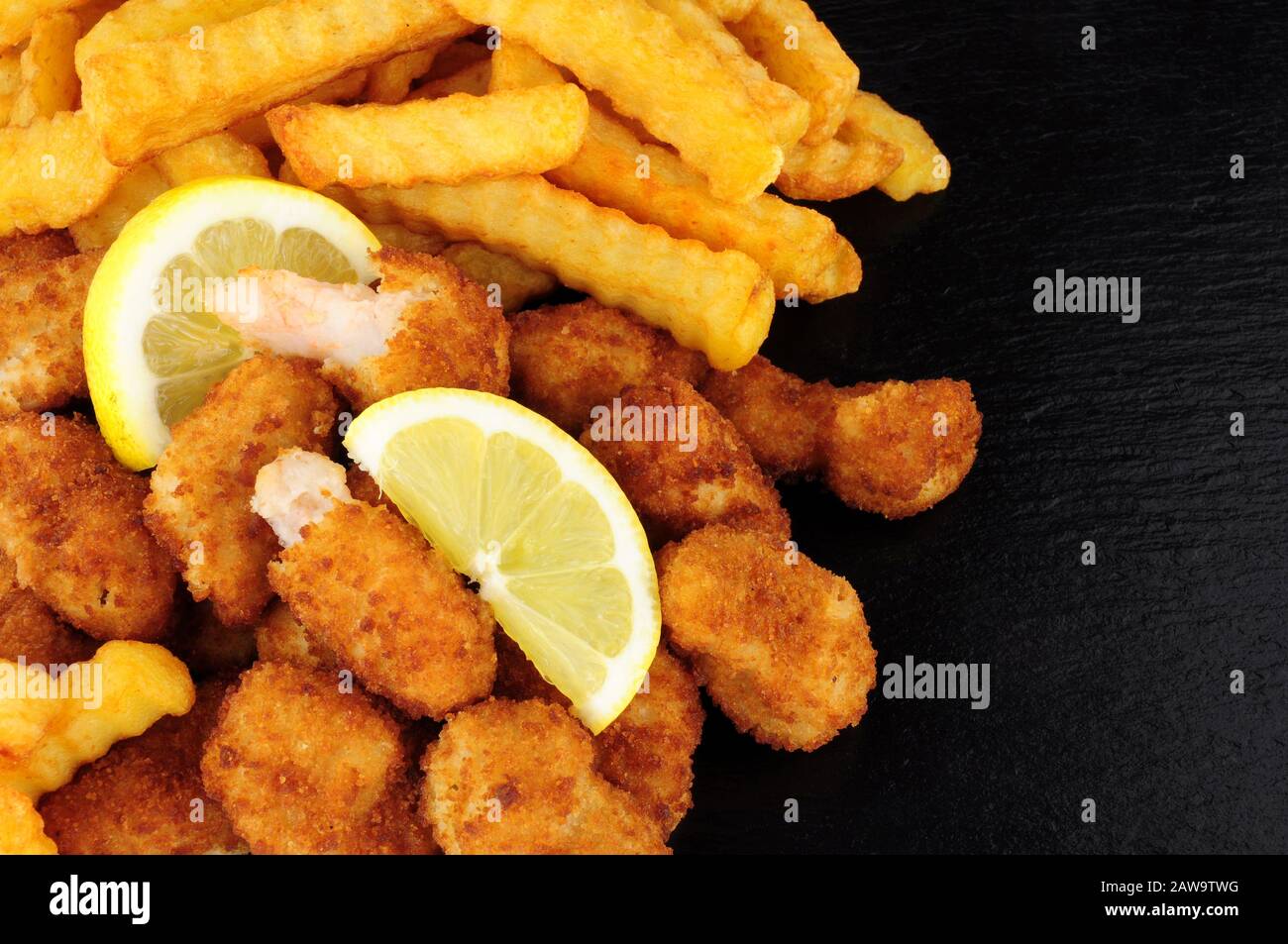 Crispy breadcrumb covered fried scampi and chips on a slate background