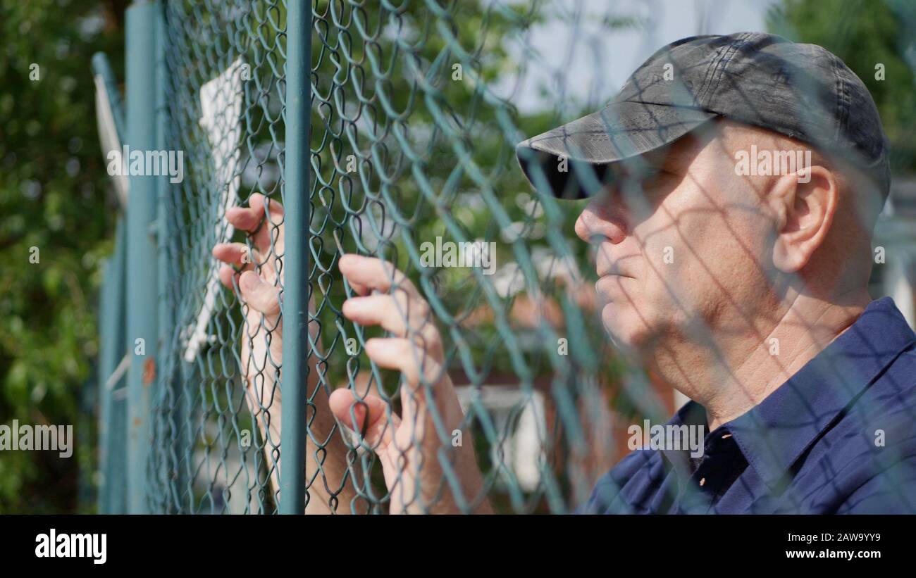 Image with a Desperate Man Looking Worried Behind a Metallic Wall, Prison Concept Stock Photo