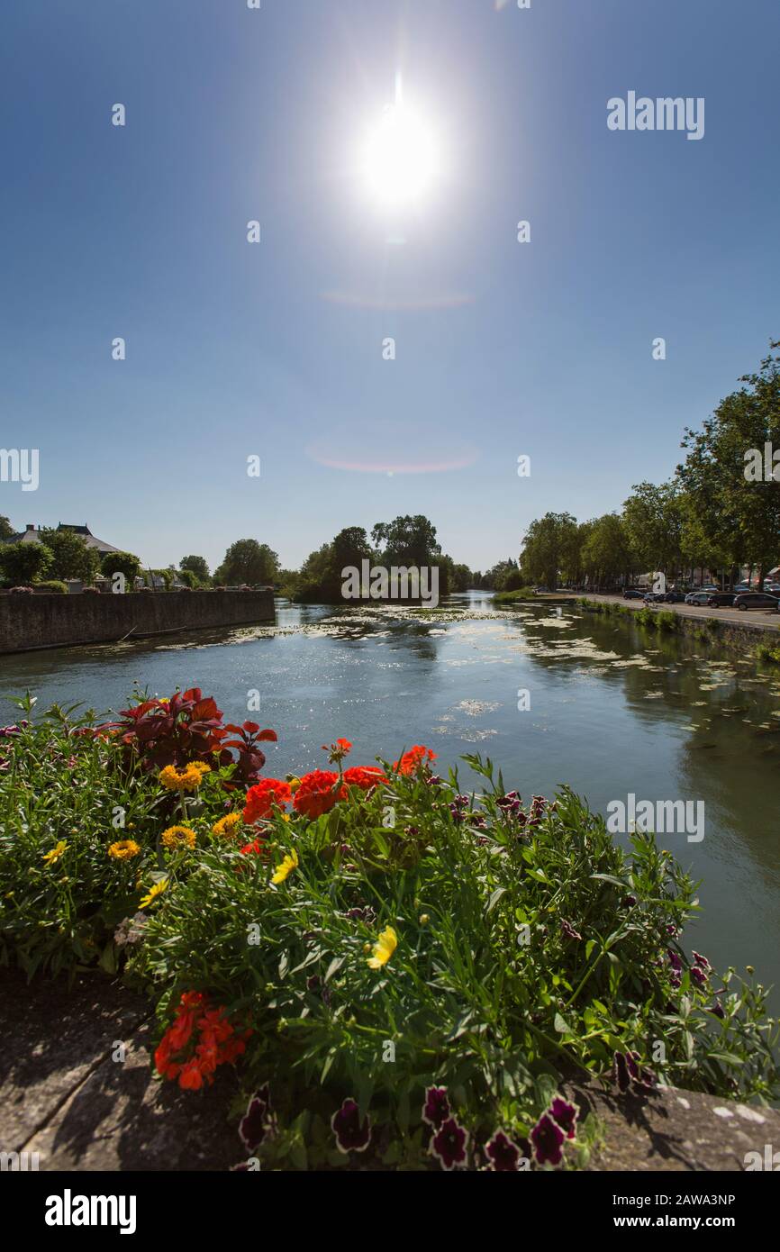 Town of La Fleche, France. Picturesque silhouetted view of flower baskets on the Loir River embankment, at the Rue du Marechal Gallieni. Stock Photo