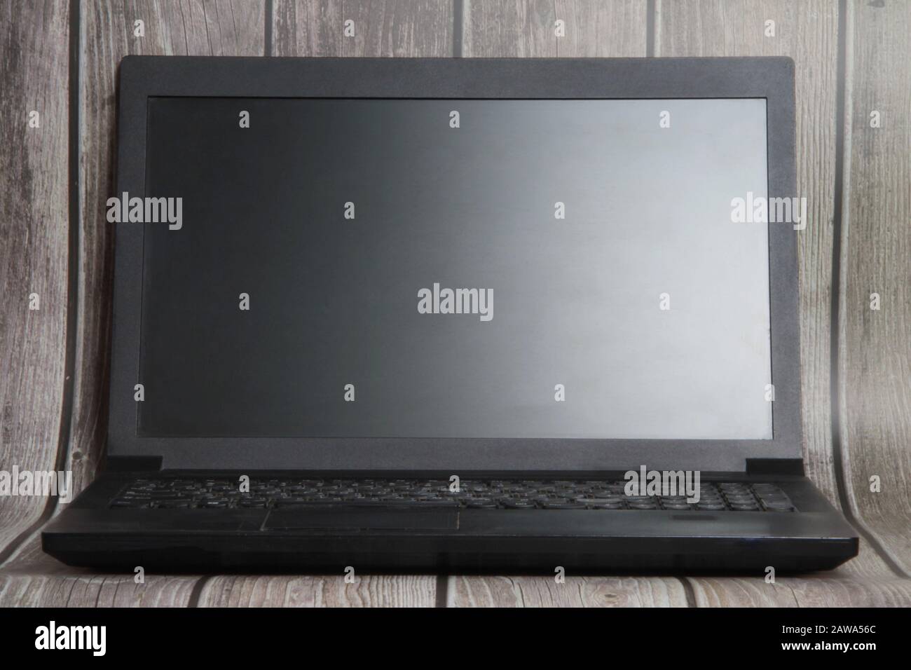 A laptop with a empty screen stands on the background of wooden boards. Place for text, layout for design. Stock Photo