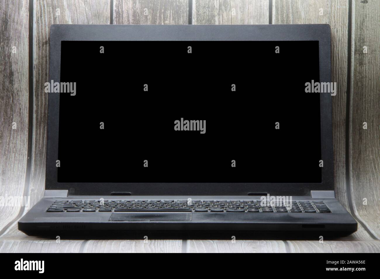 A laptop with a black screen stands on the background of wooden boards. Place for text, layout for design. Stock Photo
