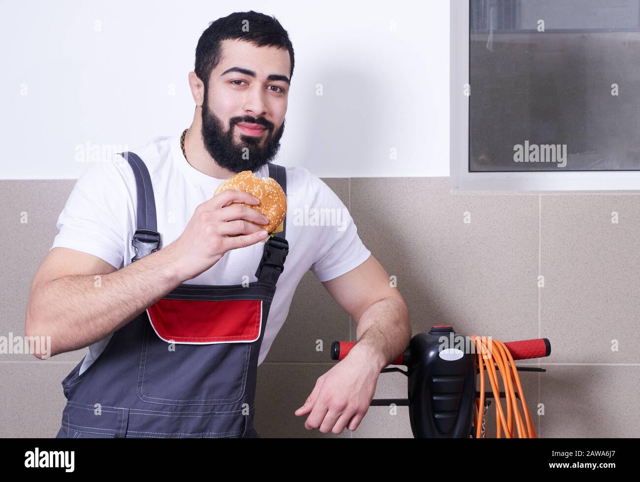 Worker wearing uniform eating burger during a lunch break Stock Photo