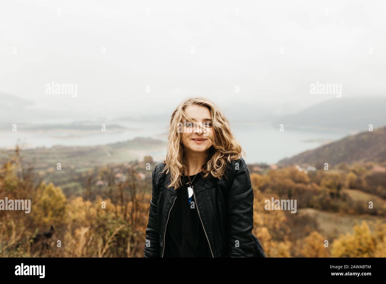 happy girl with curly blond hair dances on a lake alone, her hair is flying because of the wind flow, free as a bird. photo of girl with curly hair Stock Photo