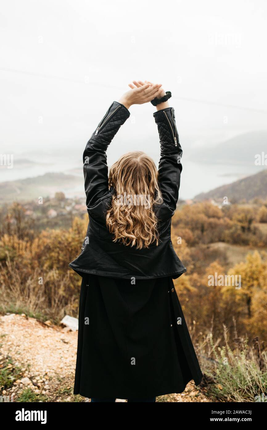 happy girl with curly blond hair dances on a lake alone, her hair is flying because of the wind flow, free as a bird. photo of girl with curly hair Stock Photo
