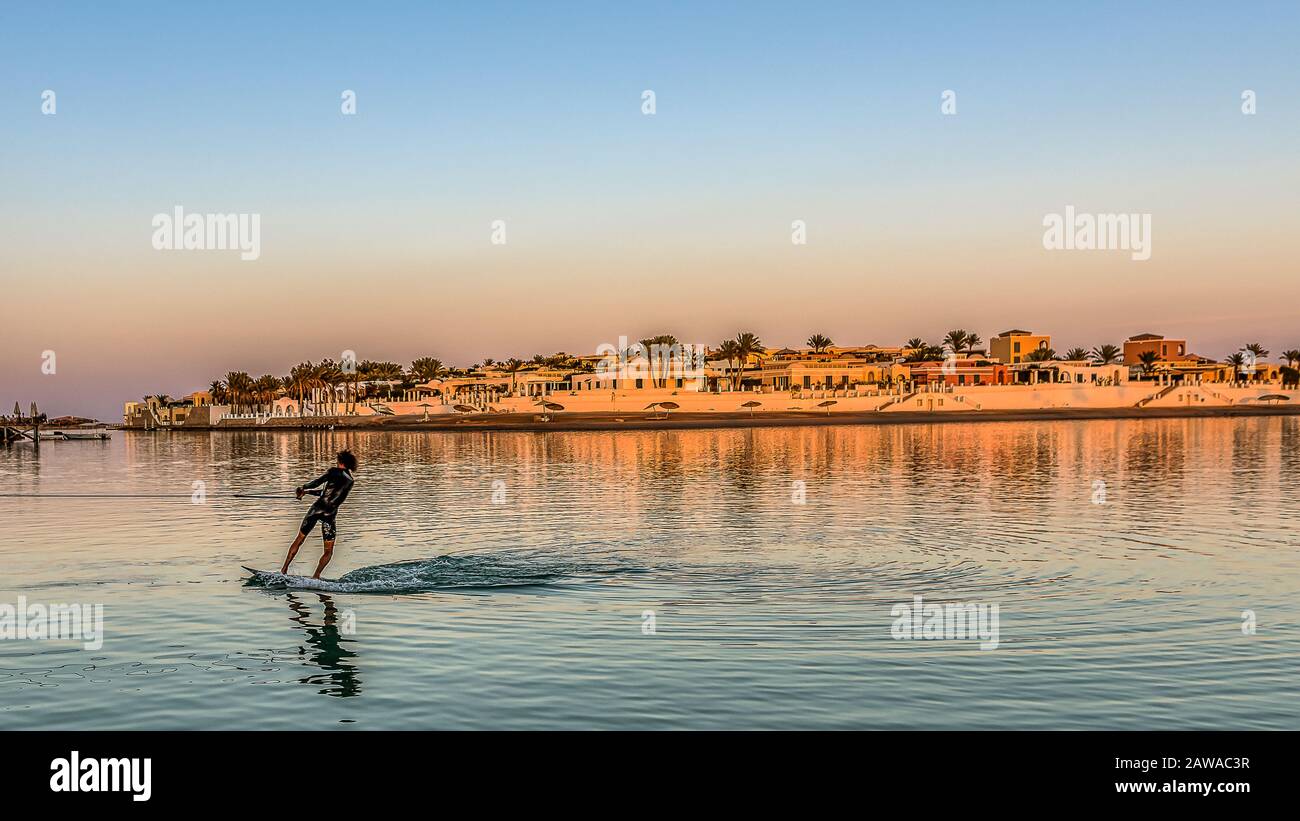 Man in a black wet suit waterskiing in the sunset in front of the arabic town , El Gouna, Egypt, January 16, 2020 Stock Photo