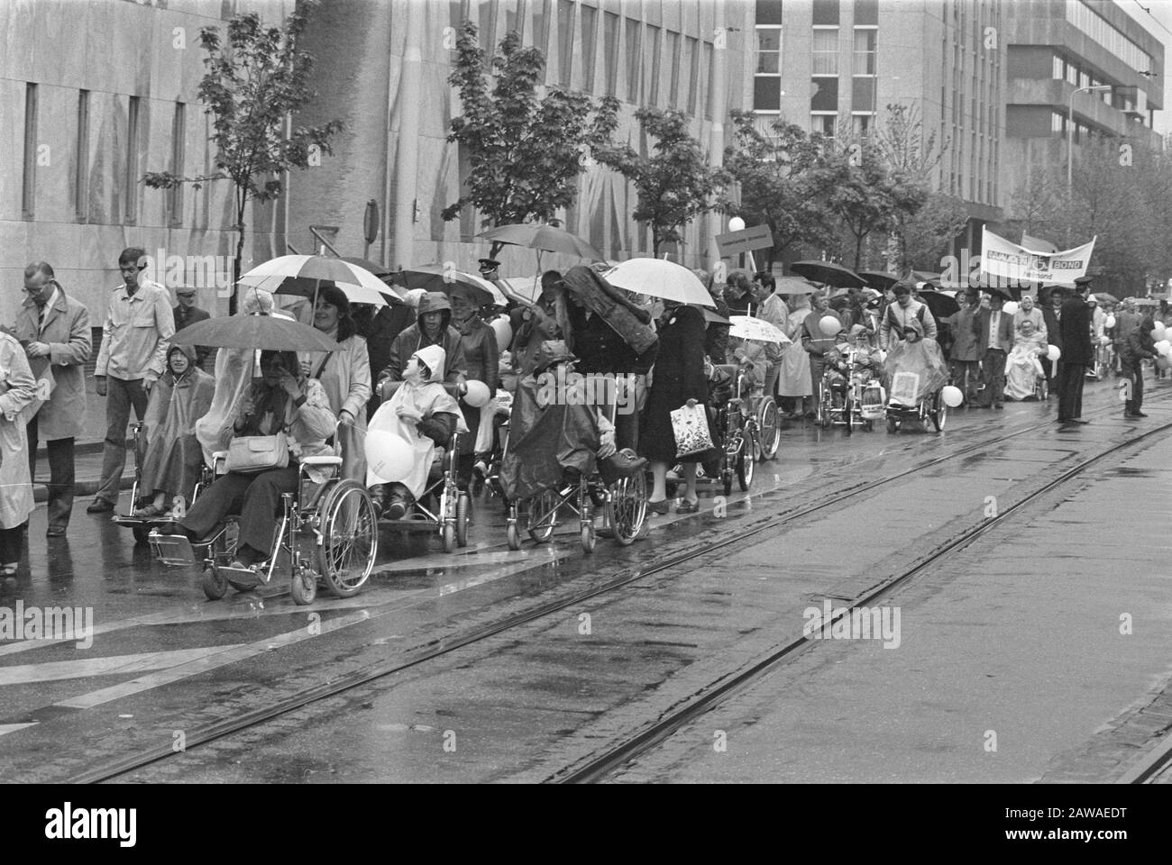 Protest disabled and incapacitated at the deterioration of the social security system in The Hague  People in a wheelchair through the city, with umbrellas against the rain date: May 28, 1983 Location: The Hague, South Holland Keywords: disability, cuts, disabled, parades, social policy Stock Photo