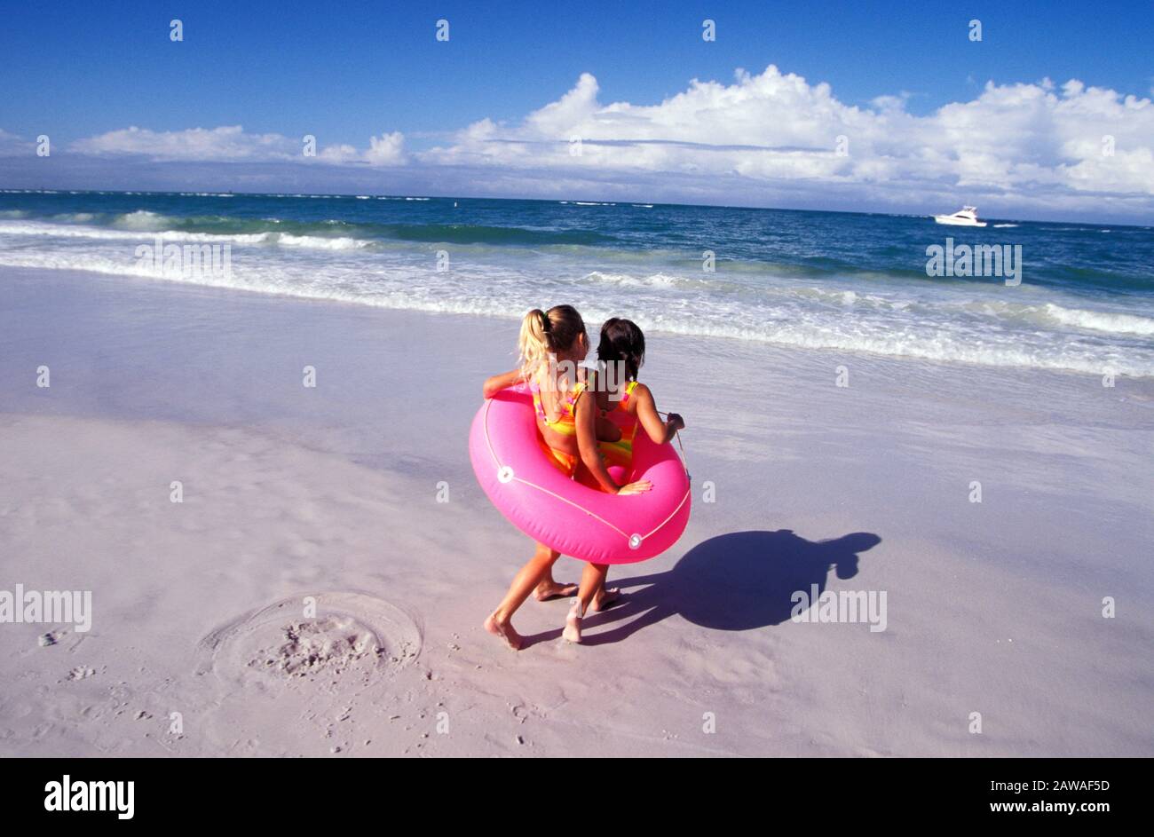 Two girls playing with an inner tube on the beach on summer vacation Stock Photo
