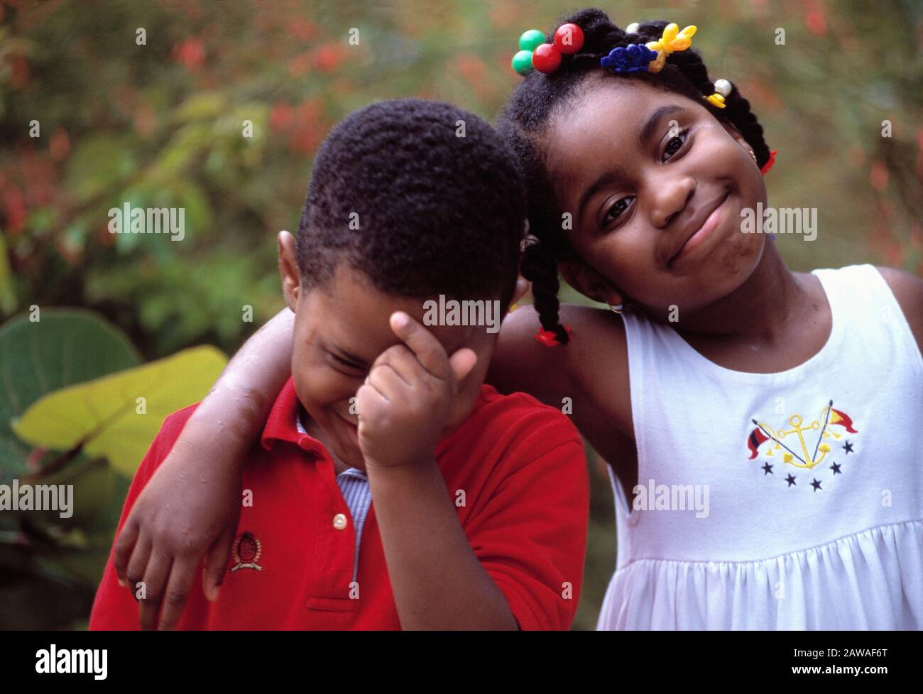 Portrait of a self confident African Americans little girl with her arms around her and embarrassed little brother Stock Photo