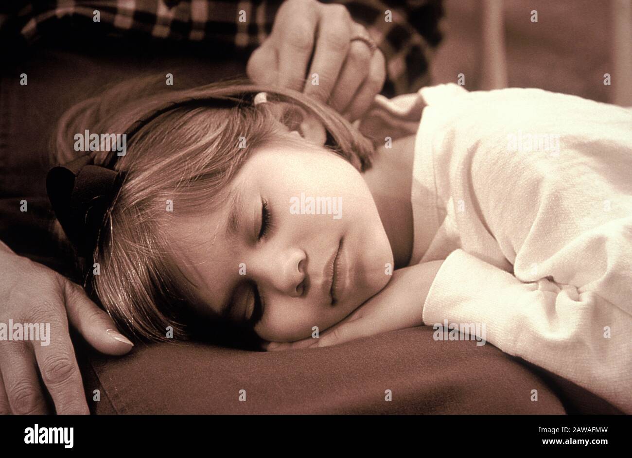 Sepia-toned image of cute little girl sleeping in the safety of her grandmother's lap Stock Photo
