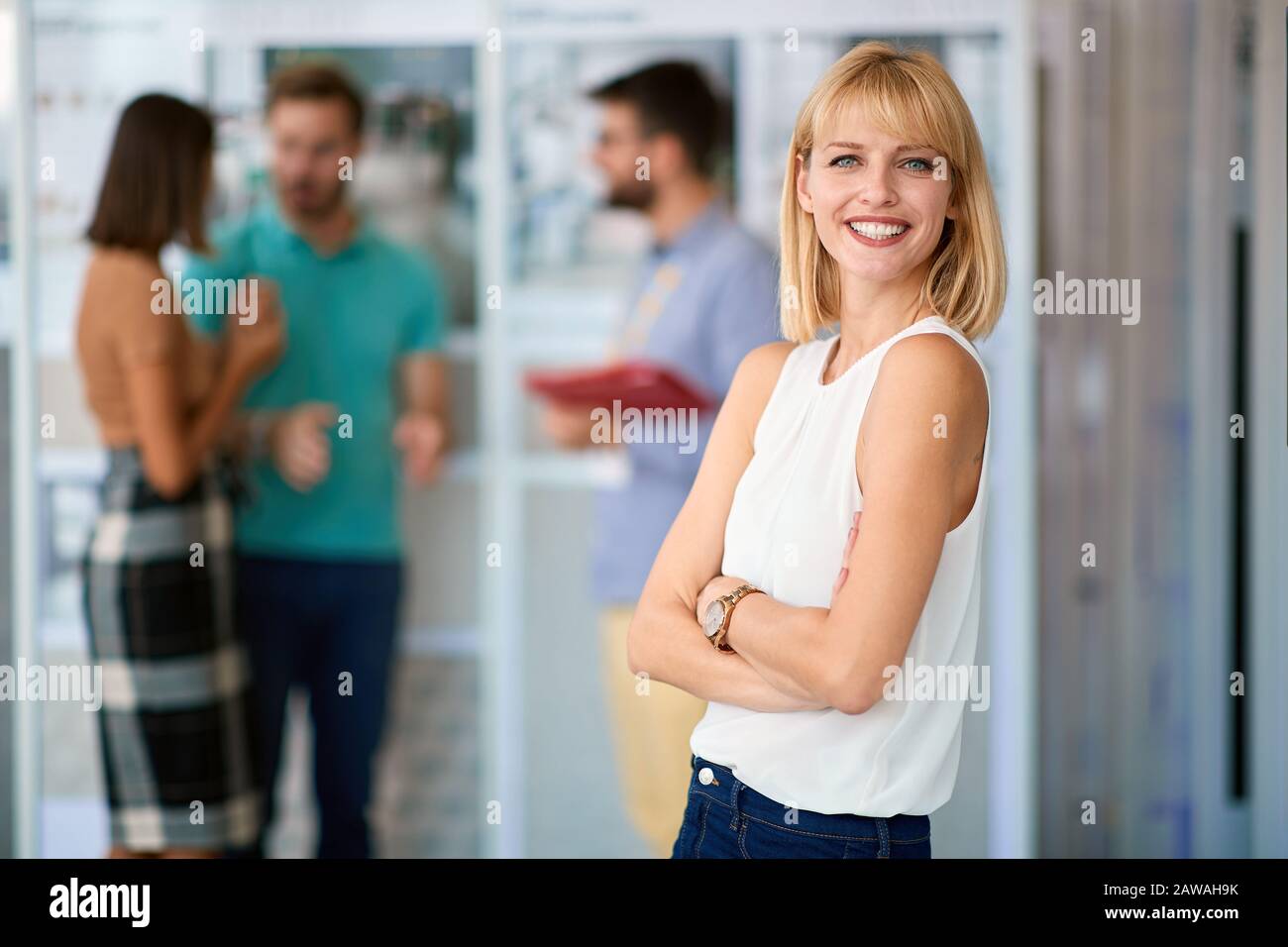 young confident handsome blonde Caucasian female watching at camera with her arms crossed in casual outfit Stock Photo