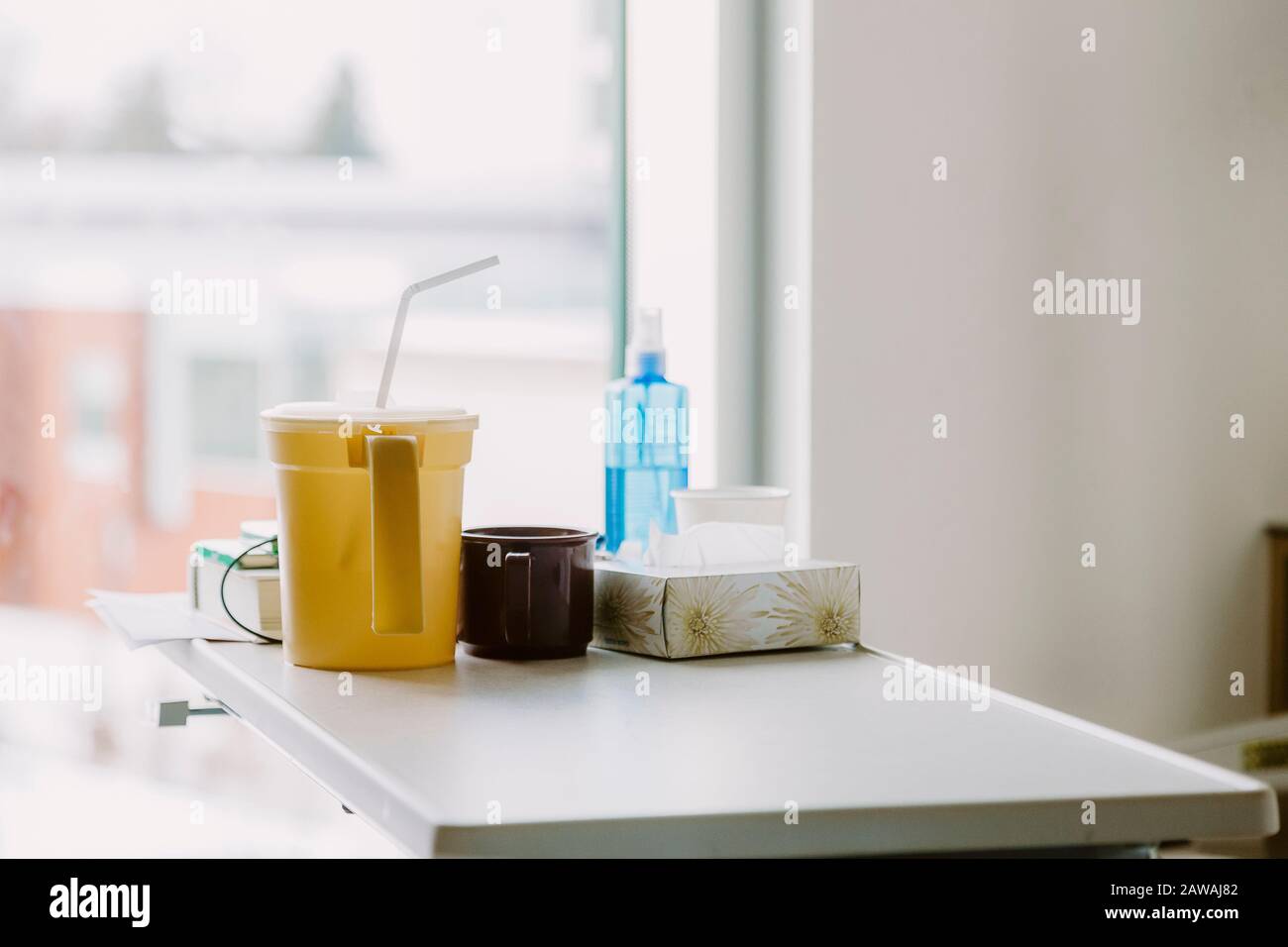 Items on bedside table in hospital room with window in background Stock Photo