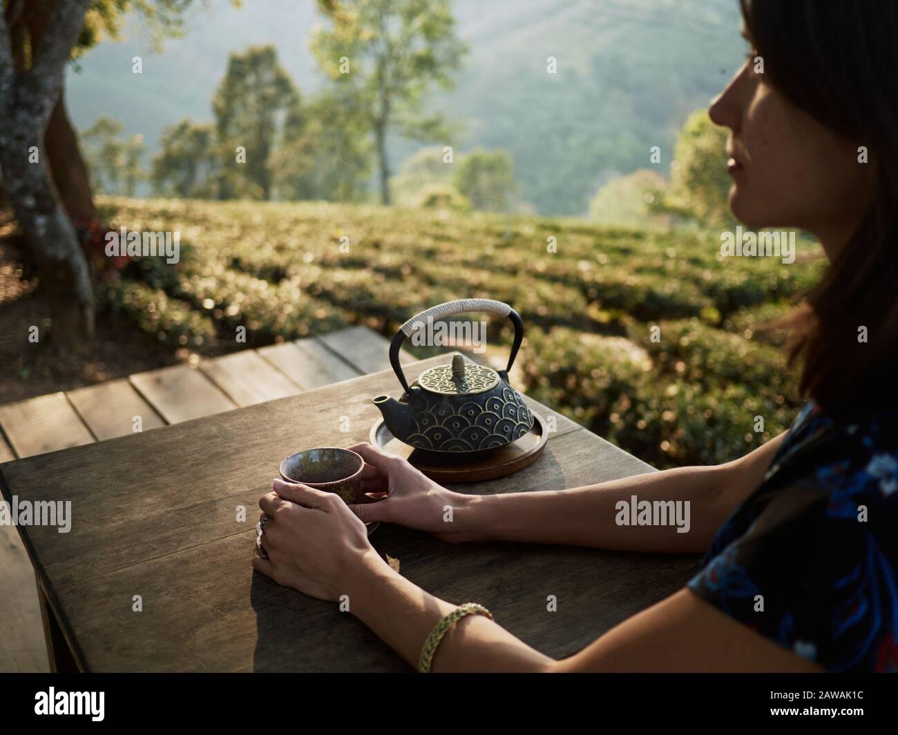 Brunette young woman drinking tea by the table in beautiful natural ...