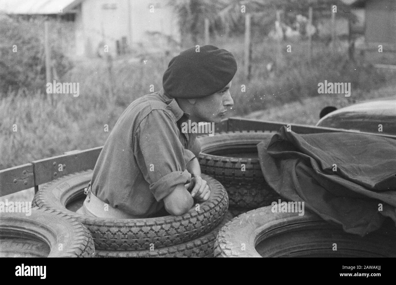 [soldier stands in a pile of tires] Date: October 1964 Location: Indonesia Dutch East Indies Stock Photo