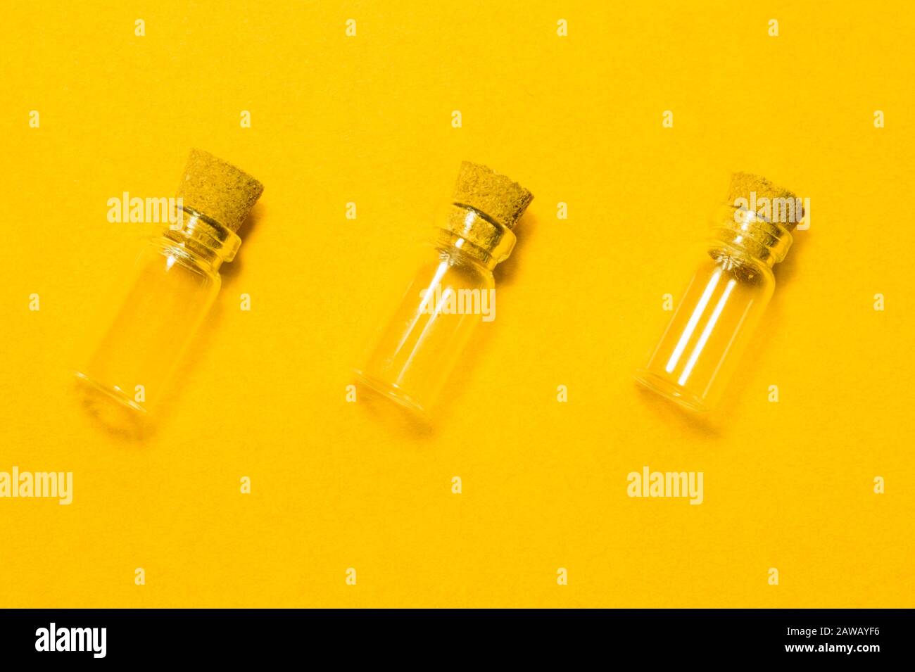 Empty little bottles with cork stopper isolated on yellow. glass
