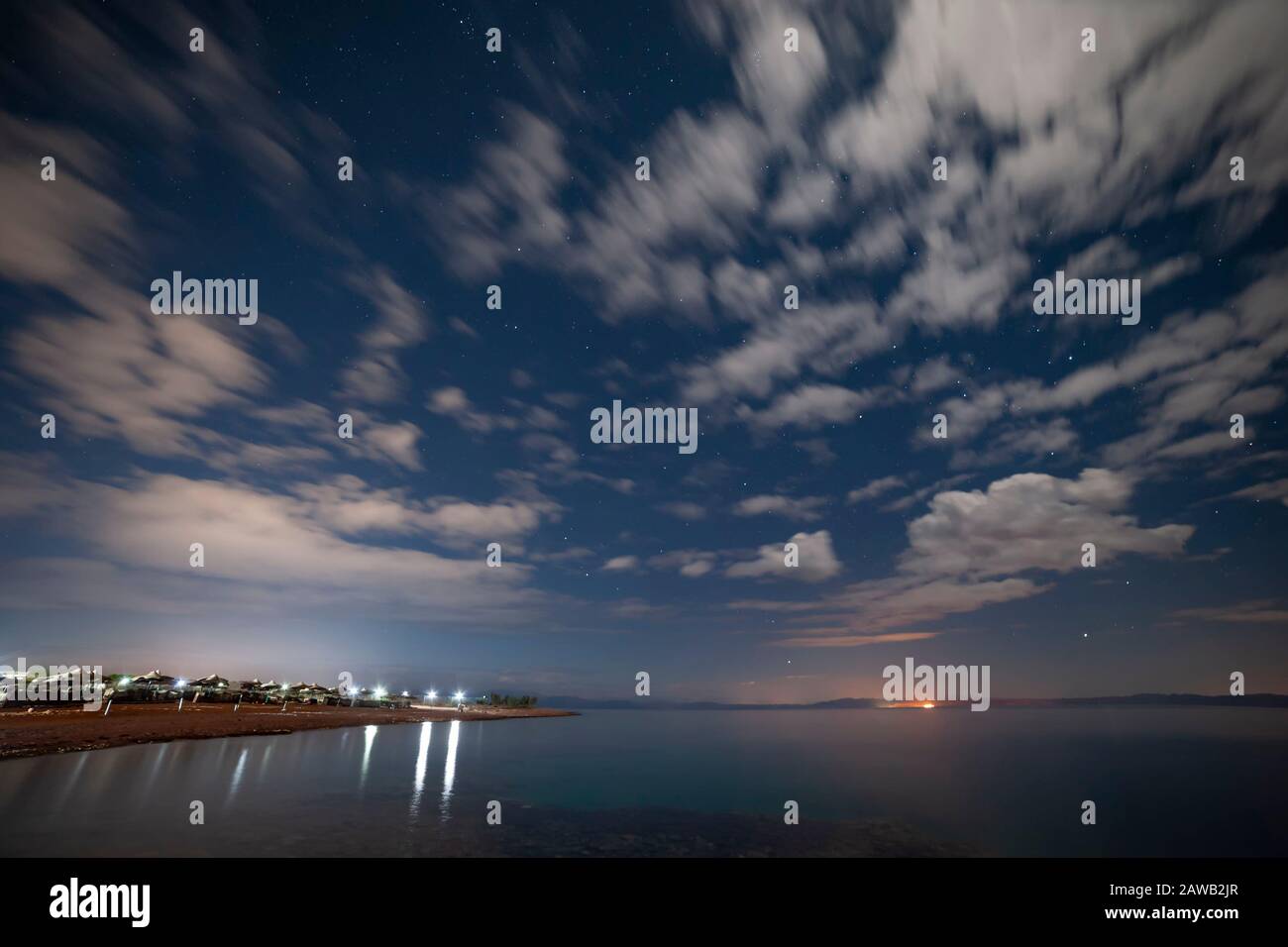 Beautiful sky with many stars and clouds over ocean. Lanterns on Red sea shore. Night landscape Stock Photo