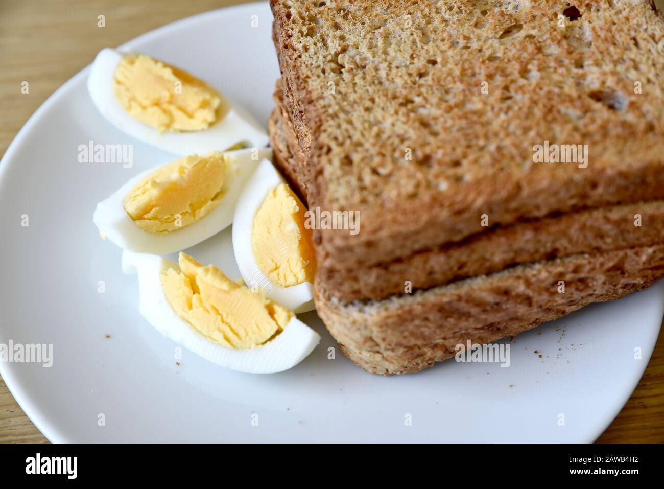Whole wheat slice toasted bread with a sliced boiled egg on the white