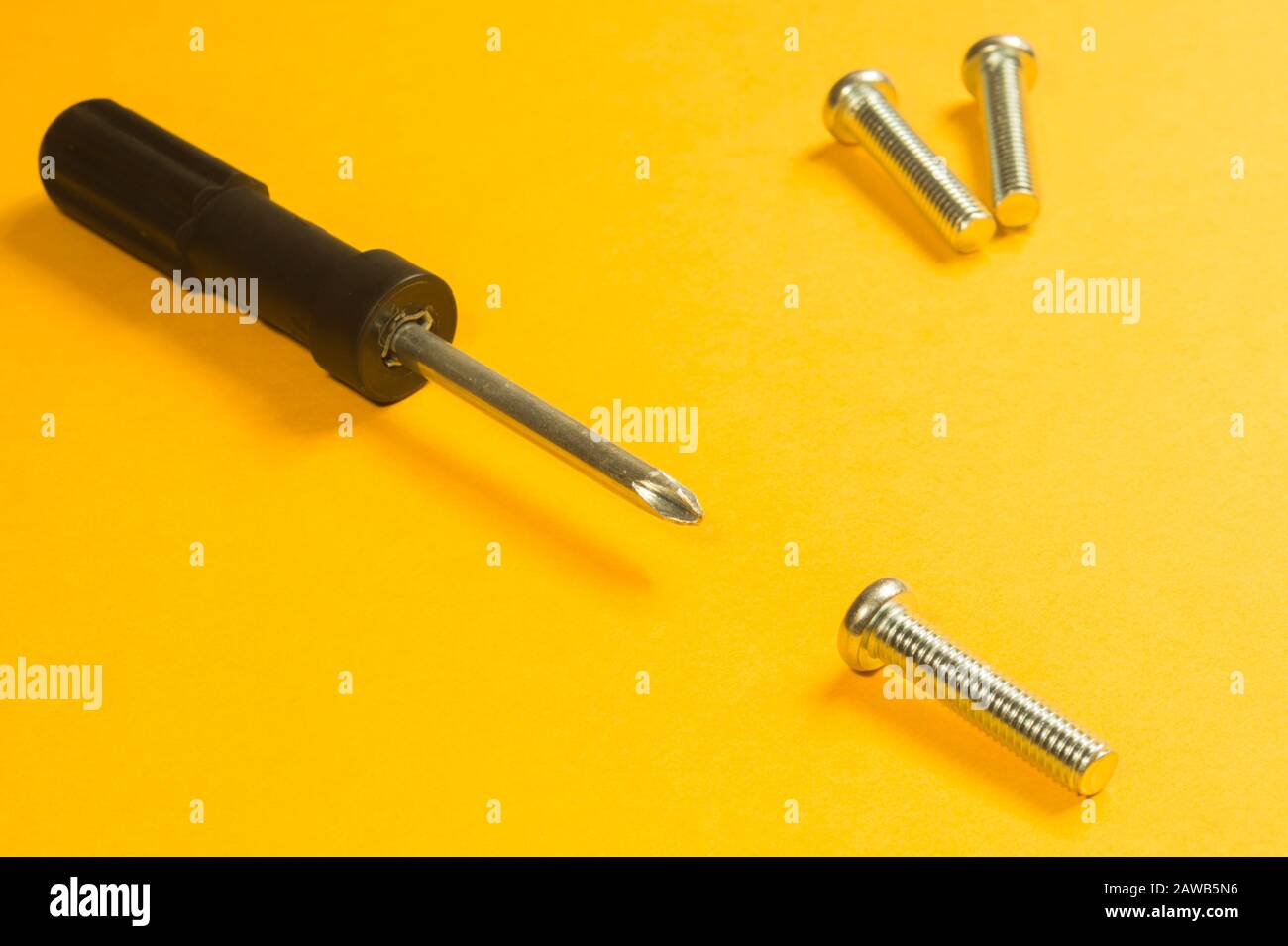 Steel screw on a yellow background. working tools Stock Photo