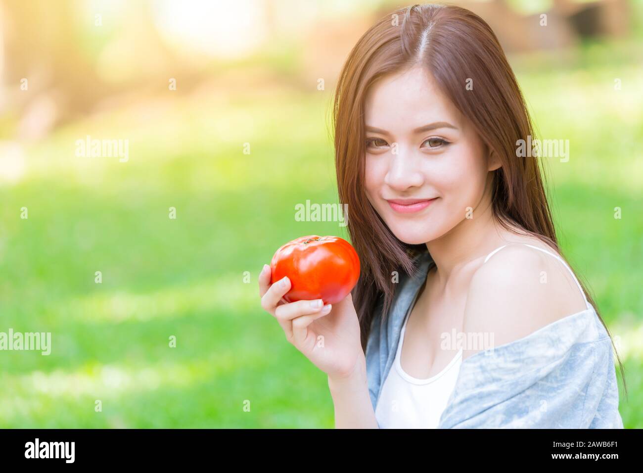 Asian Women with Tometo for healthy vegetable food high beta carotene vitamin for good health skin concept. Stock Photo