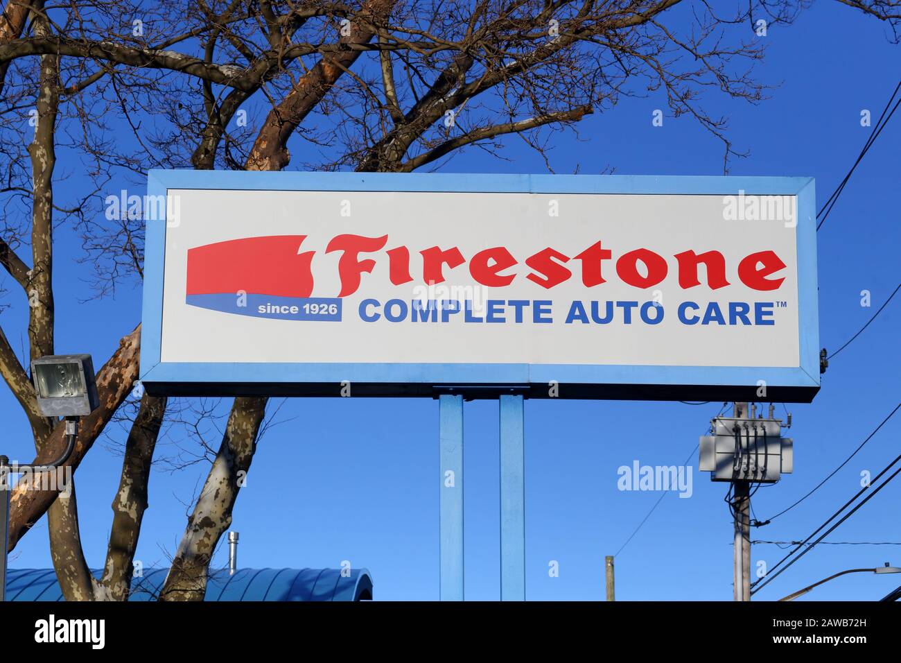 A Firestone Complete Auto Care sign on a pole against a sunny, blue sky Stock Photo