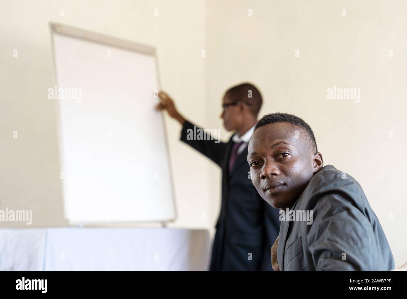Public looking at camera while African CEO presents something on a White Board Stock Photo