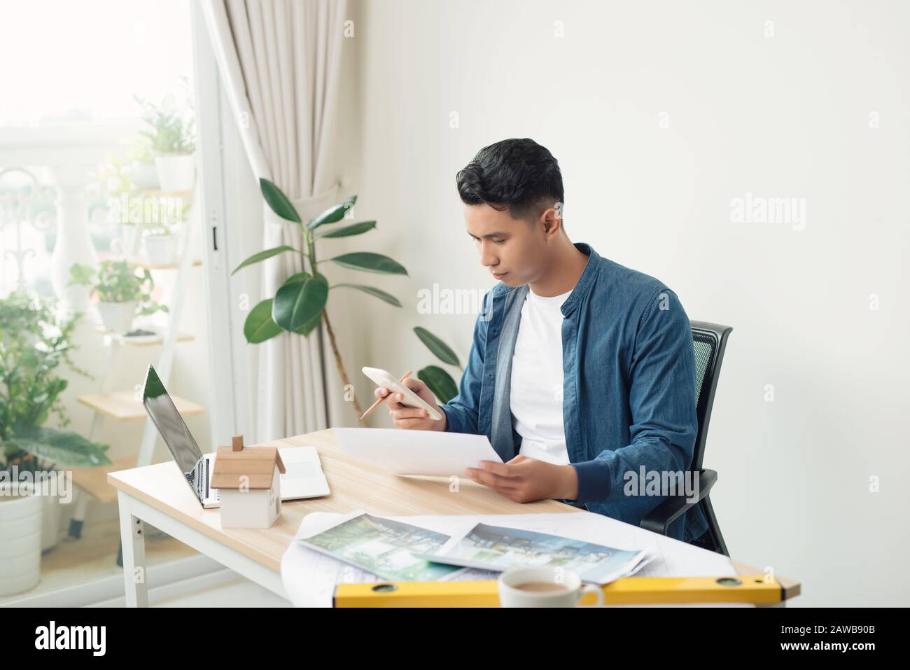 Profile shot of a young male architect working on blueprints at his desk at the office copyspace building plans construction project engineer expert s Stock Photo