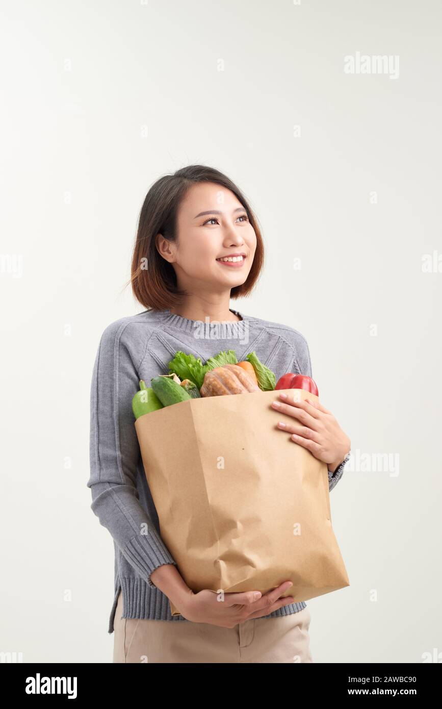 Horizontal orientation color image of a woman holding a paper bag overflowing with vegetables / Adding Veggies to your Diet Stock Photo