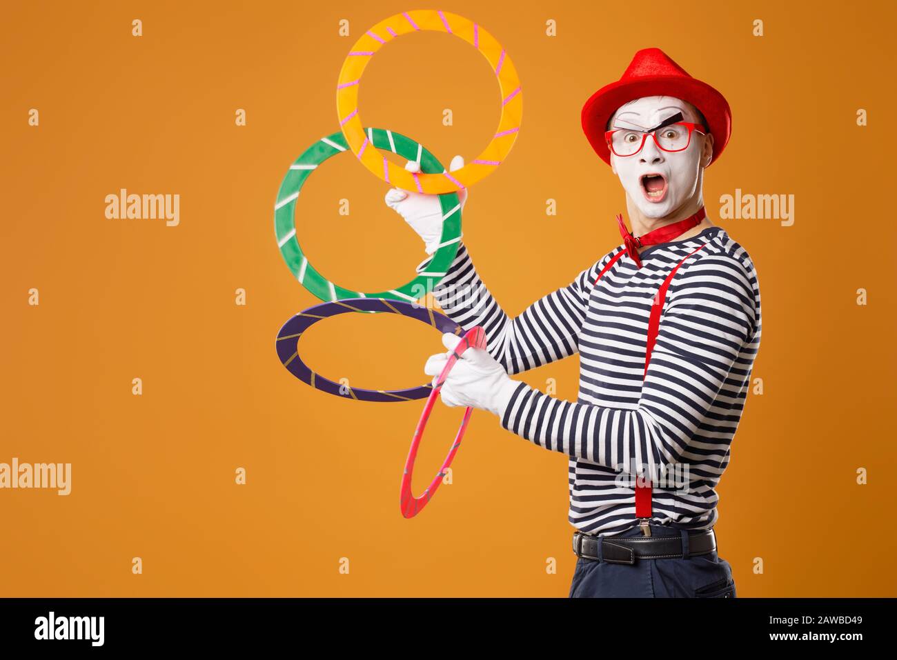 Mime man with multi-colored rings on empty orange background Stock Photo