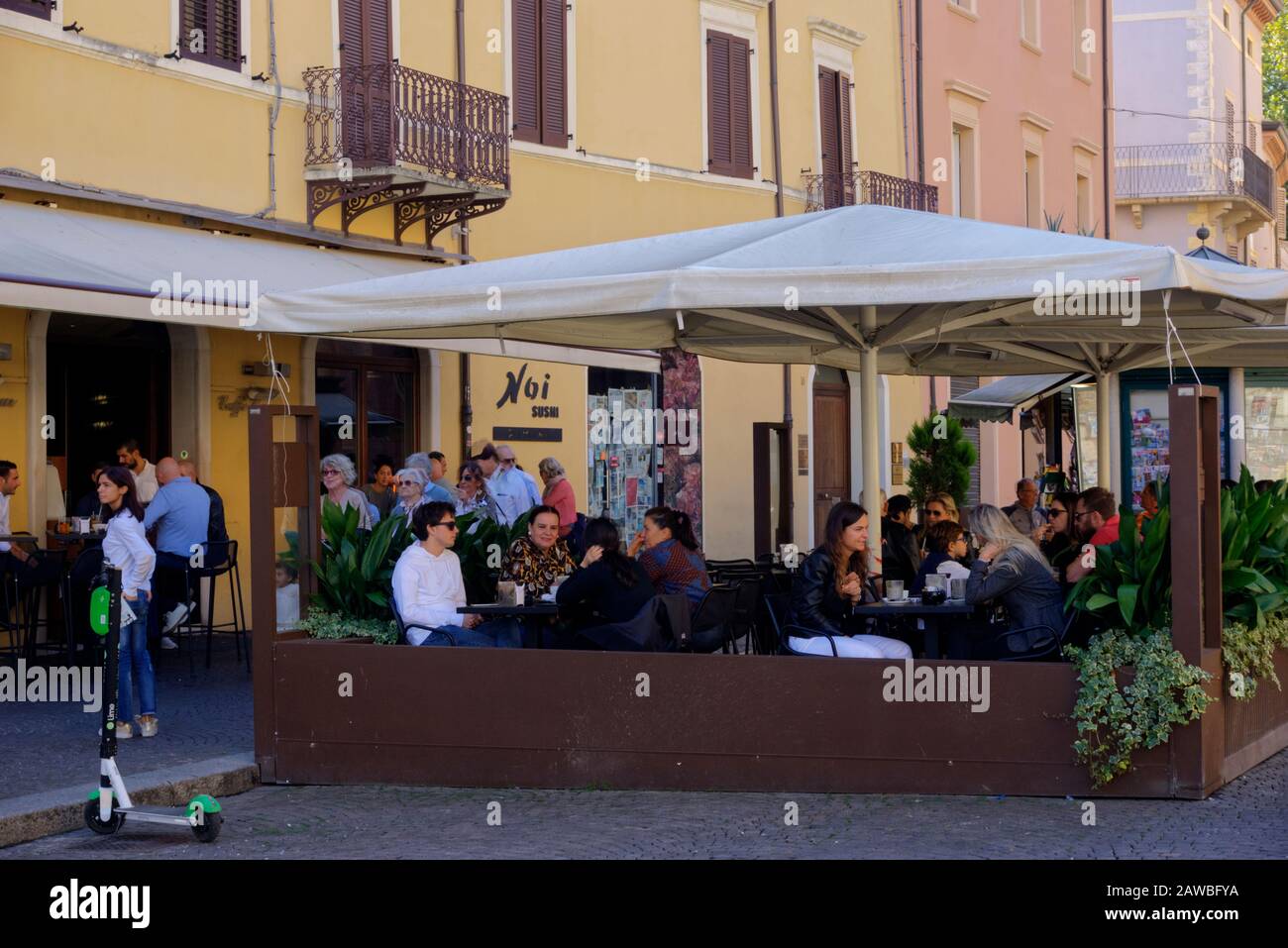 Rimini, Italy - October 20, 2019: Close up of people sitting outside cafe in Piazza Cavour (Cavour Square) with some motion blurred pedestrians Stock Photo