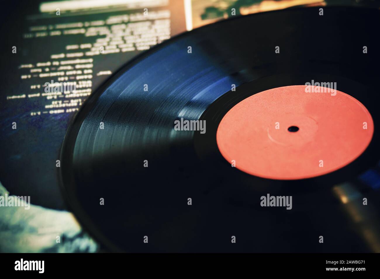 An old vintage black vinyl record lies on the cover of a music album with the playlist's text on it. Stock Photo