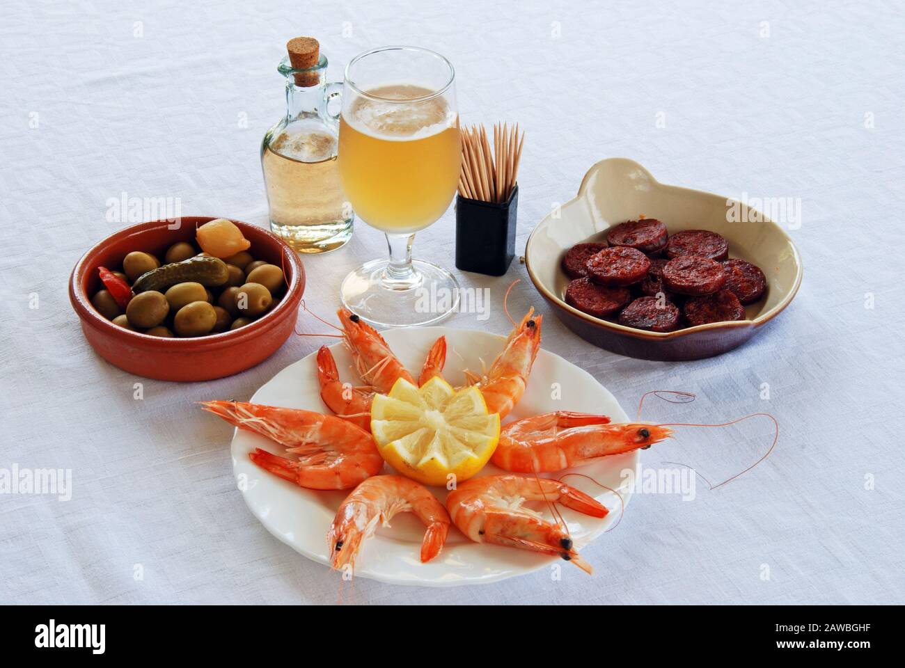 A selection of tapas with beer, King prawns with lemon, Sliced Chorizo sausage, and green olive cocktail, Costa del Sol, Spain. Stock Photo