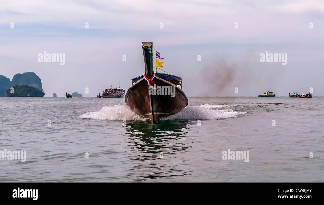 Long tail boat sailing in the sea of Ao Nang, Krabi province, Thailand, with cloud of engine smoke Stock Photo