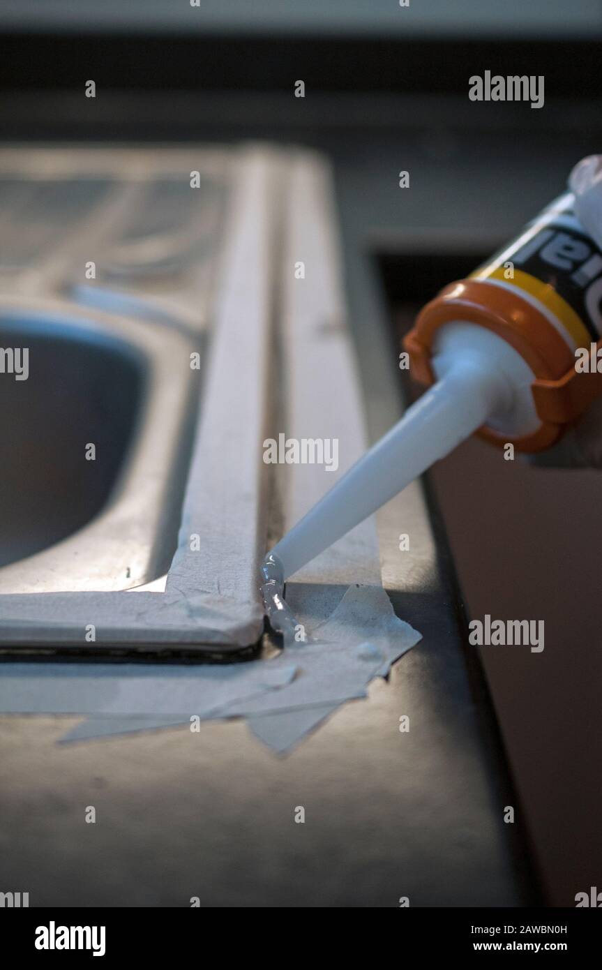 applying silicone caulk to sink Stock Photo Alamy