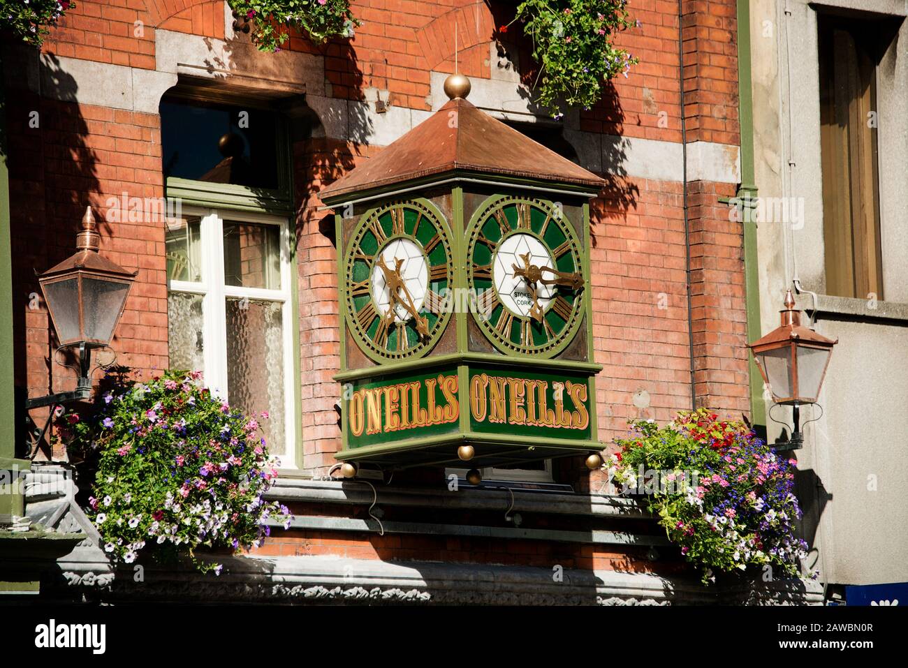 Dublin City Centre.  Clock at O'Neills  Bar Suffolk Street Dublin. Victorian style wall clock with old wall lamps and flower baskets Stock Photo