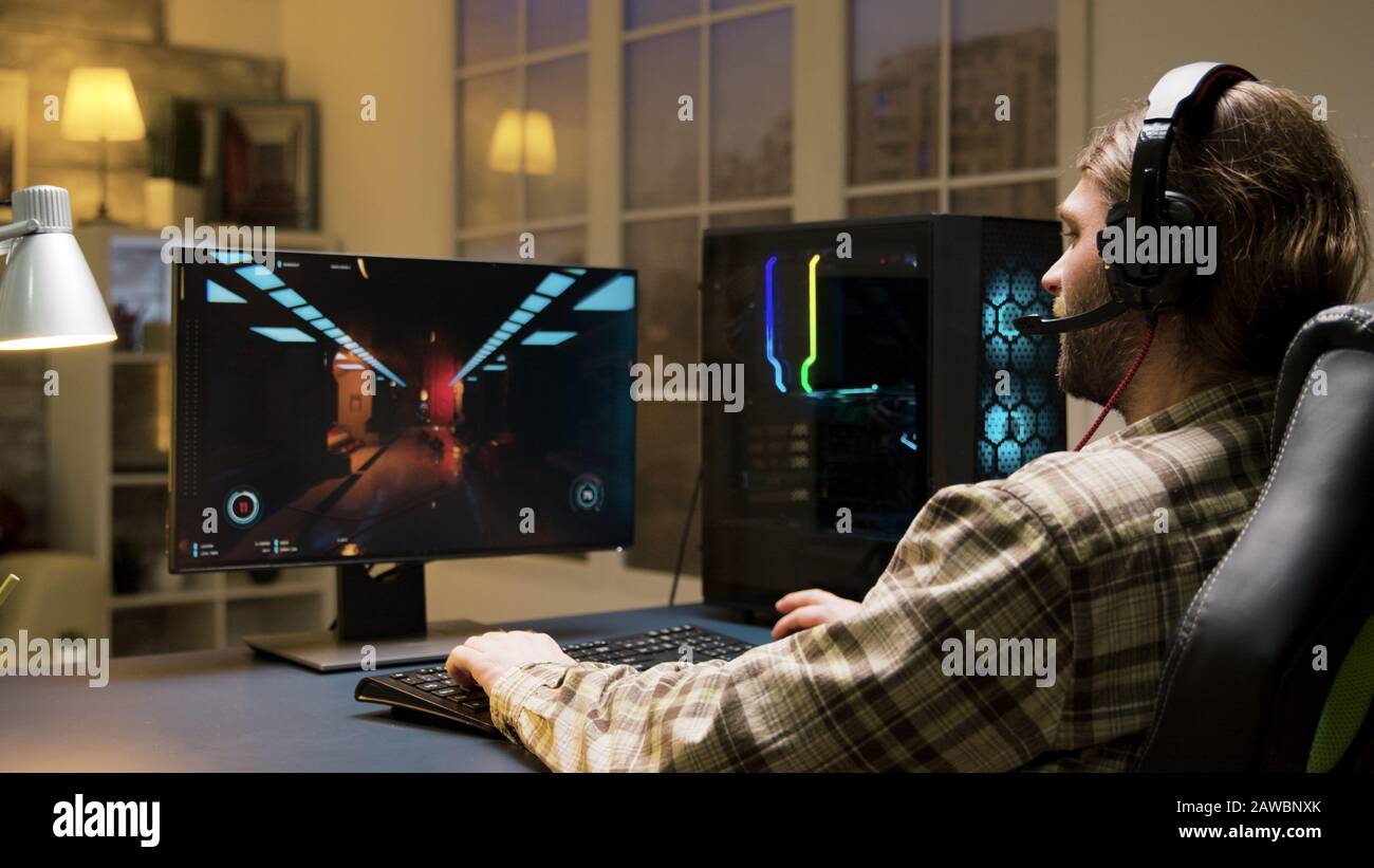 Male with headphones playing online video games talking with other players. Game over for man playing games sitting on gaming chair. Stock Photo