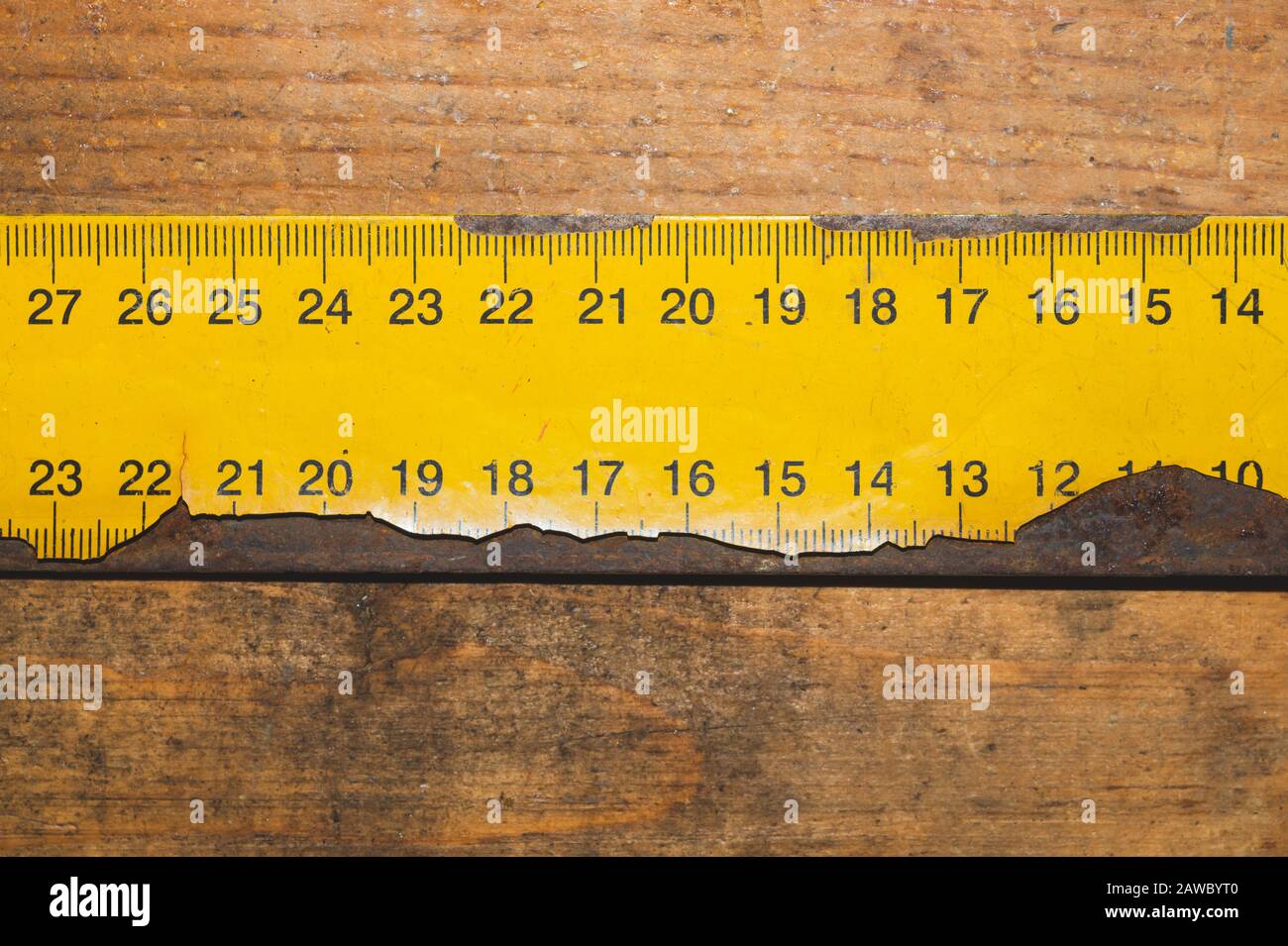 Old rusty yellow ruler with black numbers on a working wooden table ...