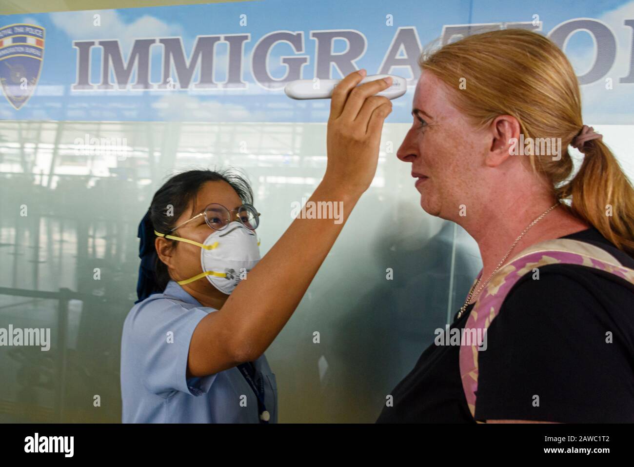 Phuket Airport, Thailand. 31 January 2020.  A member of security staff wears a surgical masks as she screens passengers with aforehead thermometer, in an attempt to prevent the spread of 2019-nCoV COVID-19 COVID 2019 nCoV Coronavirus Corona Virus during the current epidemic. Stock Photo