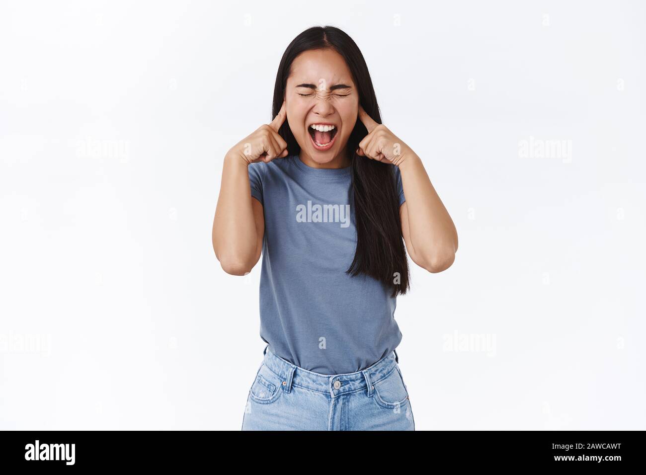 Distressed and fed up asian teenage girl with long dark hair, screaming losing temper, cant control emotions, close eyes and yelling, close ears with Stock Photo